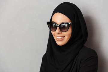 Portrait closeup of muslim fashion woman 20s in religious headscarf and sunglasses smiling and...