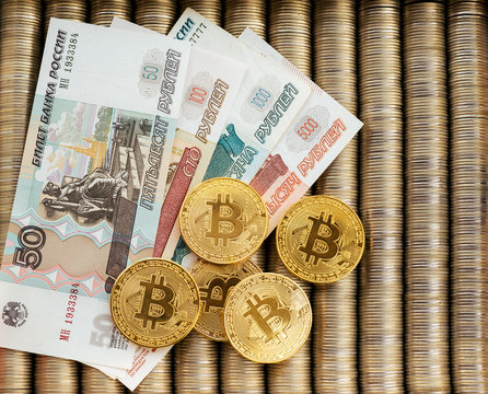 Golden crypt coins bitcoin BTC, paper denominations of Russian rubles. Metal coins are laid out in smooth background each other, close-up view from the top, crypto currency exchange of money.