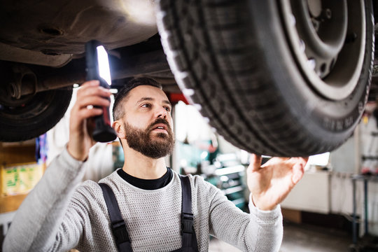 Man mechanic repairing a car in a garage.