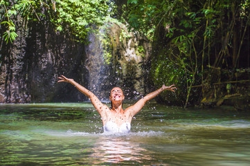 attractive happy white tourist woman enjoying playing with water and splash at tropical exotic waterfall lagoon holidays travel concept