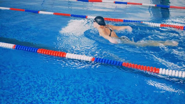 A woman workouts in a pool, swimming. 4K.