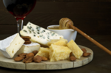 Cheese plate with nuts and honey on dark background.
