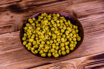 Ceramic plate with canned green pea on wooden table