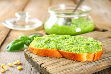 Homemade pesto sauce, bread. Ingredients. Cheese, garlic, basil, pine nuts, olive oil on an old wooden table.
