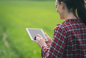 Farmer woman with tablet in green field