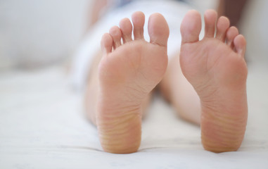 Feet of women sleeping on bed.