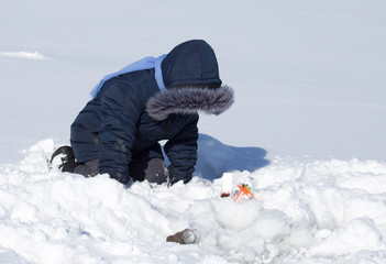 Fototapeta na wymiar A boy on ice is fishing in the winter