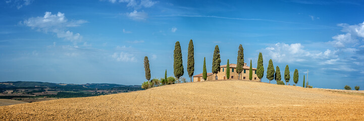 Typical landscape of a farm with a row of cypress trees in Tuscany, Italy