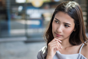 Fototapeta premium serious thoughtful woman thinking an idea; portrait of serious and stressed woman looking up, thinking, planning, finding good idea or decisive plan; young adult asian woman model