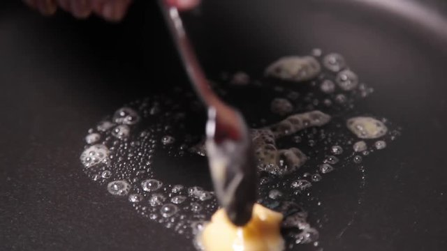 A close up shot of a butter sliding on a pan bt using a spoon.