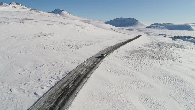 Car driving through icy icelandic landscape in wintertime.