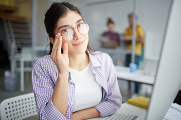 Portrait of young casual worker in eyeglasses sitting at office