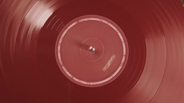 The vinyl record on DJ turntable record player close up. Macro. View from above. Fragment of a rotating red vinyl plate record player. The moment of a spinning vinyl  plate. Loop