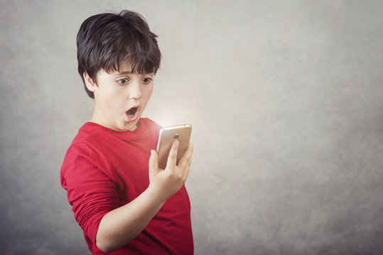 ni&ntilde;o sorprendido con un tel&eacute;fono m&oacute;vil