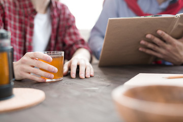 Close-up of men drinknig tea at the table and looking in book