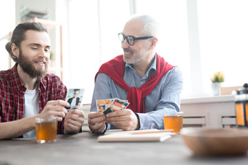 Two smiling coworkers looking photographies at the table and drinking tea