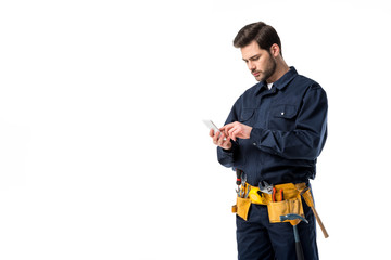 Professional plumber with tool belt using smartphone isolated on white