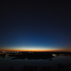 Night sky with stars above the river during the spring flood. View of the starry space.