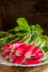 A bunch of radishes in an iron plate on a wooden background. Rustic style.