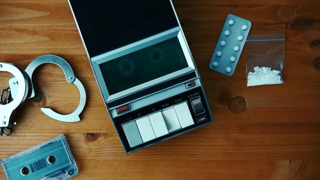 Drug related police arrest concept, top view with tape player playing cassette with suspect's statement during police interrogation.