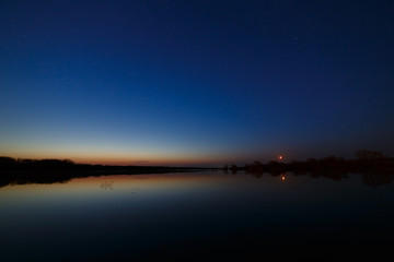 Fototapeta na wymiar Sky with the stars before dawn. Night landscape with a lake.