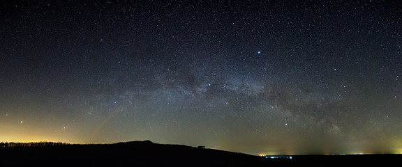 Stars of the Milky Way galaxy in the night sky above the skyline. Panoramic view of the starry...