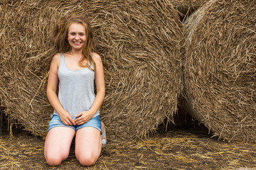 A smiling young woman with a blond with disheveled hair on the background of hay. Copy space. Nasty hair concept.
