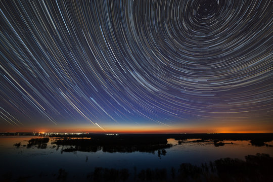 Star trails in the night sky. A view of the starry space in the background of the river.