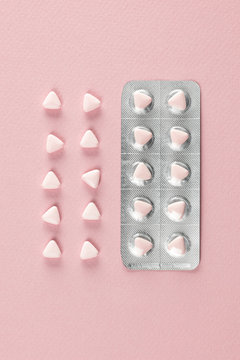 Pink pills and blister arranged on paper