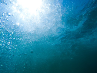 Underwater bubbles with sunlight through water surface, natural scene