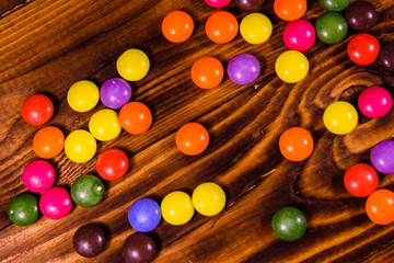 Fototapeta na wymiar Pile of the multicolored candies on a wooden table. Top view