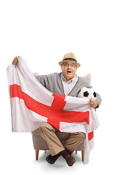 Excited elderly soccer fan sitting in an armchair and holding an English flag