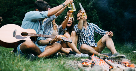 Fototapeta premium Group of friends camping and sitting around camp fire
