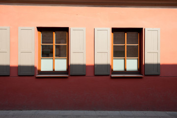 Old windows with shutters on a red building. Sunny photo in the summer