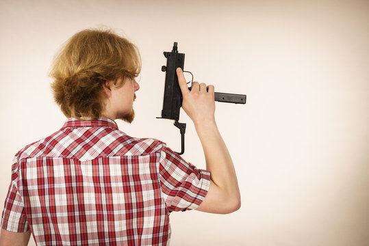Man standing backwards holding gun