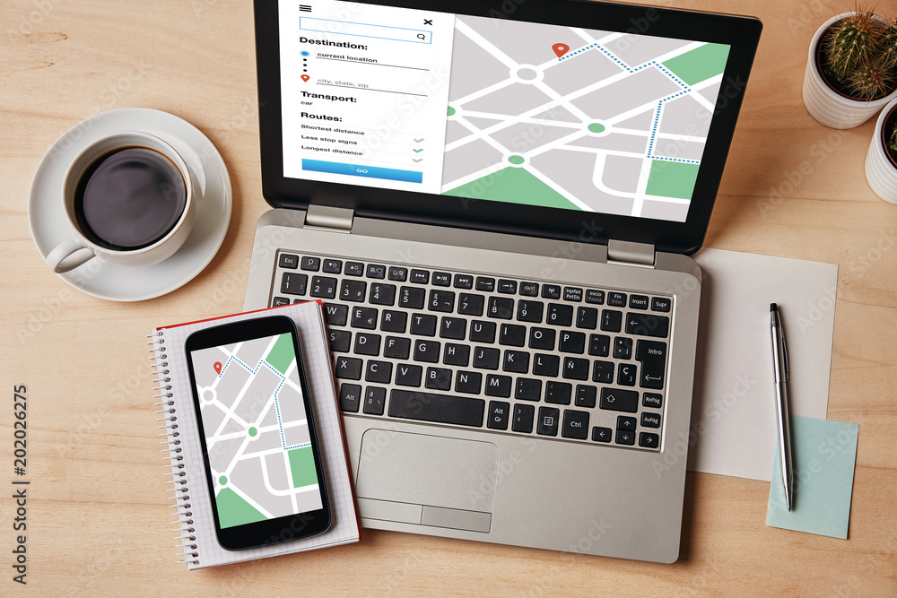 Wall mural gps map navigation app on laptop and smartphone screen over wooden table. location tracker concept. 