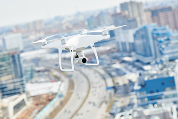 drone quadcopter with digital camera hovering over city