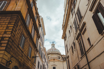 Fototapeta premium old buildings on street of Rome with cathedral on background, Italy