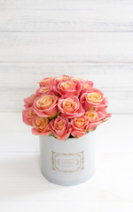 Beautiful pink roses in a round box. Peach roses in a round box. Roses in a round box on a white wooden background. Roses in a Hat Box