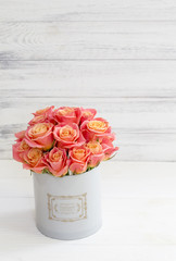 Beautiful pink roses in a round box. Peach roses in a round box. Roses in a round box on a white wooden background. Roses in a Hat Box