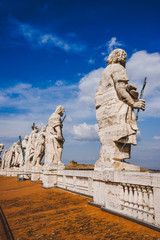 Fototapeta na wymiar statues on top of St Peters Basilica on blue sky, Vatican city, Italy