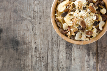 Muesli and dried fruit in wooden bowl on wooden table. Top view. Copyspace