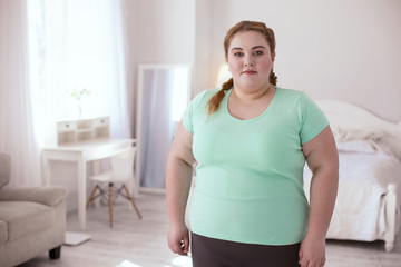 Fototapeta na wymiar Healthy lifestyle. Plump young woman wearing sports clothing standing in the room