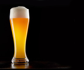 Single tall stylish glass of chilled frothy wheat beer