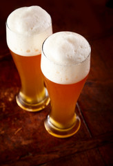 Two tall glasses of wheat beer with good frothy heads