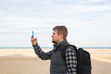 Traveler man taking photos to the beach with smartphone camera on summer travel vacation or hike to...