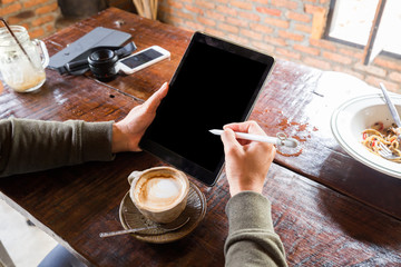 Fototapeta na wymiar Man hand use tablet blank screen on wood table with hot latte