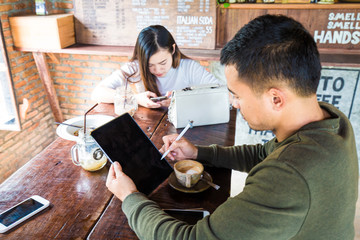 Business man in casual use tablet black screen with latte coffee on wood table