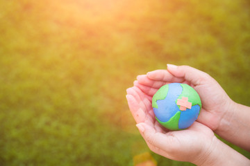 World Earth Day concept. Woman hand holding handmade globe on green grass field background.