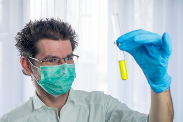 weird looking doctor holds yellow liquid test tube in his hand, concept dangerous medicine. selective focus